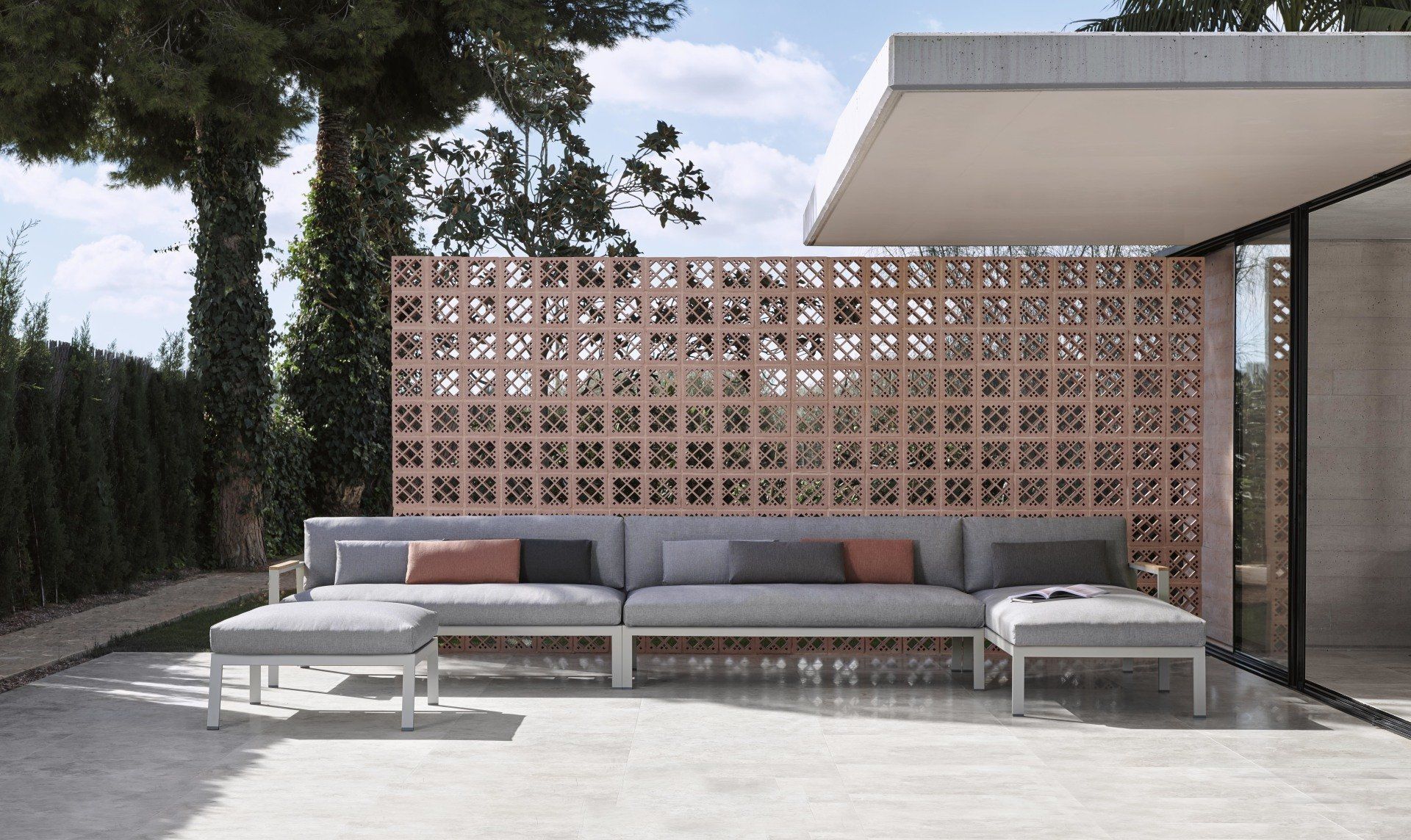 Eine Terrasse mit einer Couch und einem Ottoman vor einer Backsteinmauer