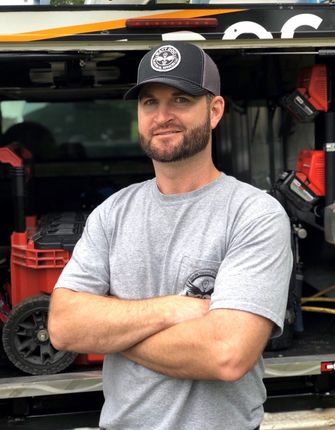 A man is standing in front of a truck with his arms crossed.