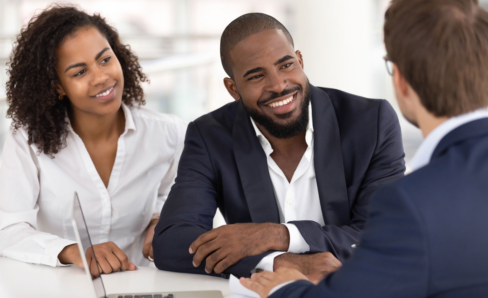 Happy african american young family couple listen to realtor insurer