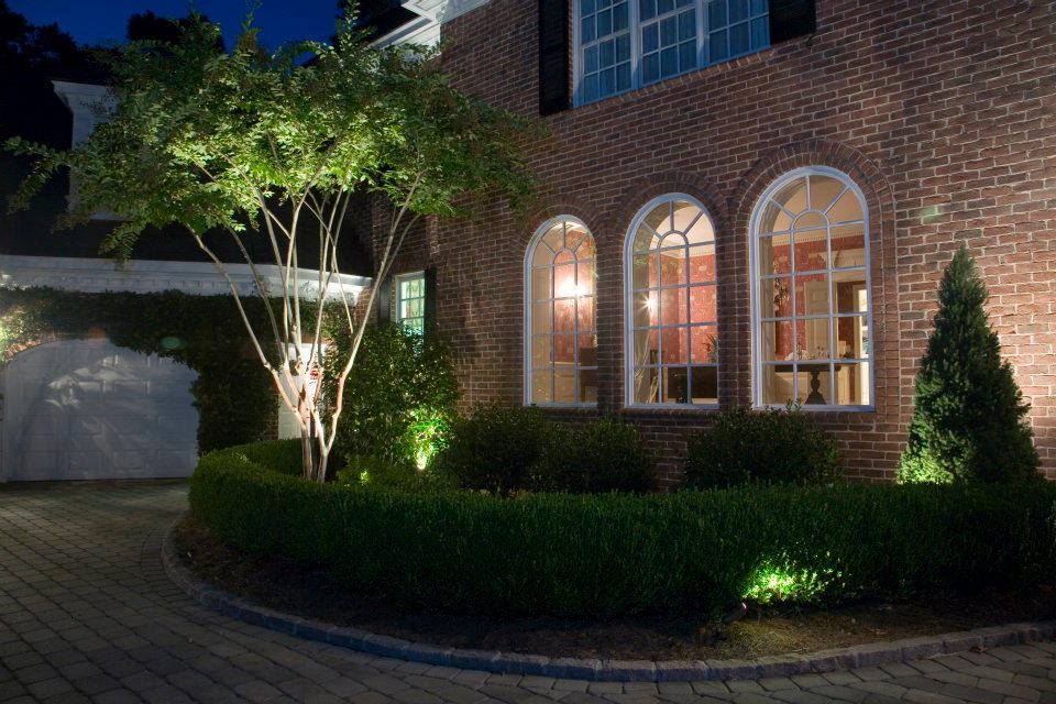 House Being Lit Up By Landscape Lighting Next To Tree And Trimmed Bushes — Virginia Beach, VA — Gentle Rain House Being Lit Up By Landscape Lighting Next To Tree And Trimmed Bushes — Virginia Beach, VA — Gentle Rain