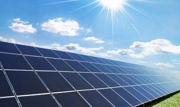 Paneles solares contra un cielo azul con el sol brillando intensamente.