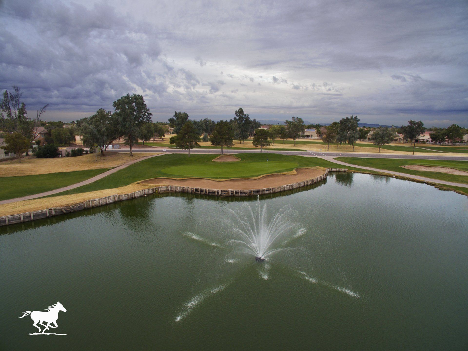 An aerial view of a golf course with a fountain in the middle of the lake.