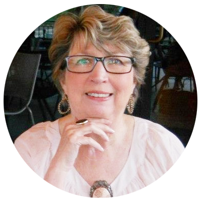 Wanda Patterson, white woman with short blonde hair wearing glasses and a pink blouse