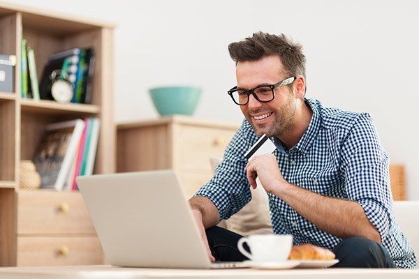 Financial Help — Happy Man Sitting On Sofa With Laptop in Winter Haven, FL Financial Help — Happy Man Sitting On Sofa With Laptop in Winter Haven, FL