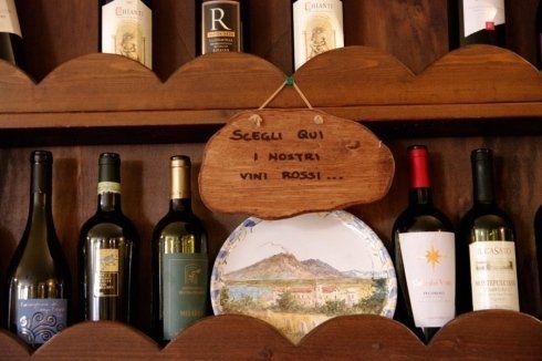 scaffale di vino con scritto scegli qui i nostri vini rossi