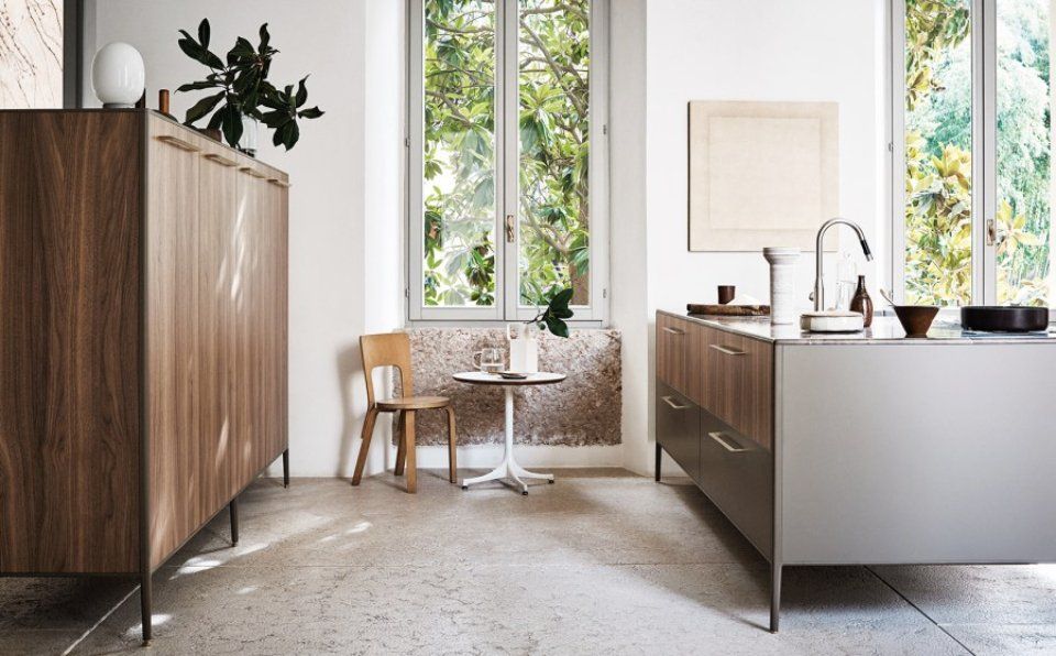 Cucina moderna con mobili in legno, isola e ampia finestra.