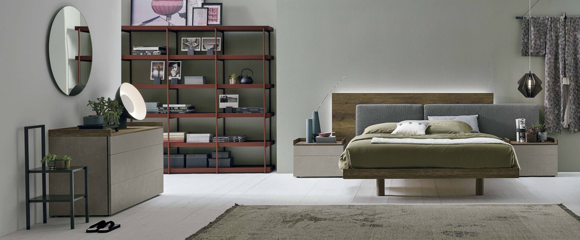 Camera da letto con letto moderno, cassettiera, scaffalatura e specchio rotondo; colori neutri.