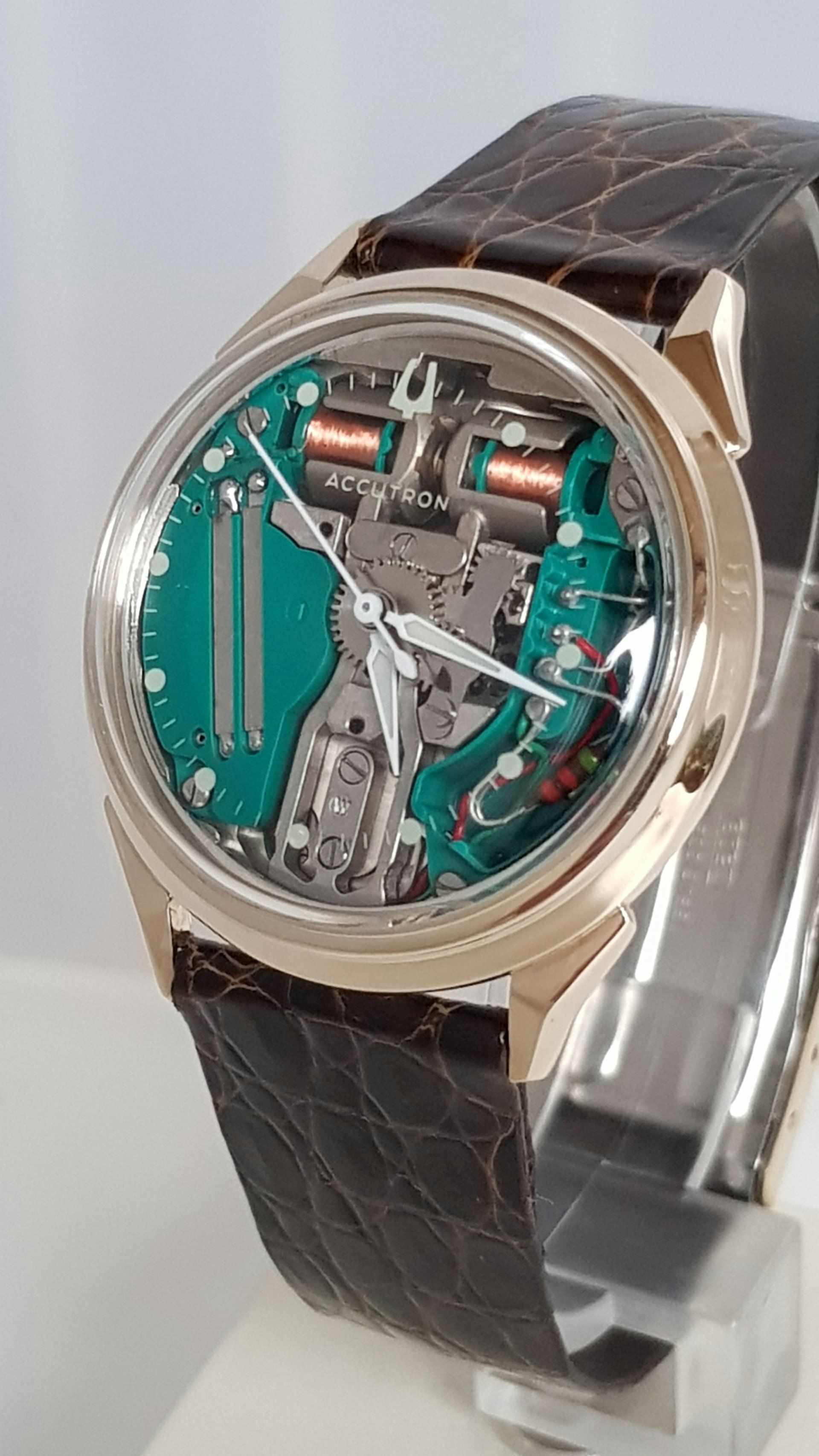 Luxury wristwatch with transparent face, teal inner dial, and brown leather strap