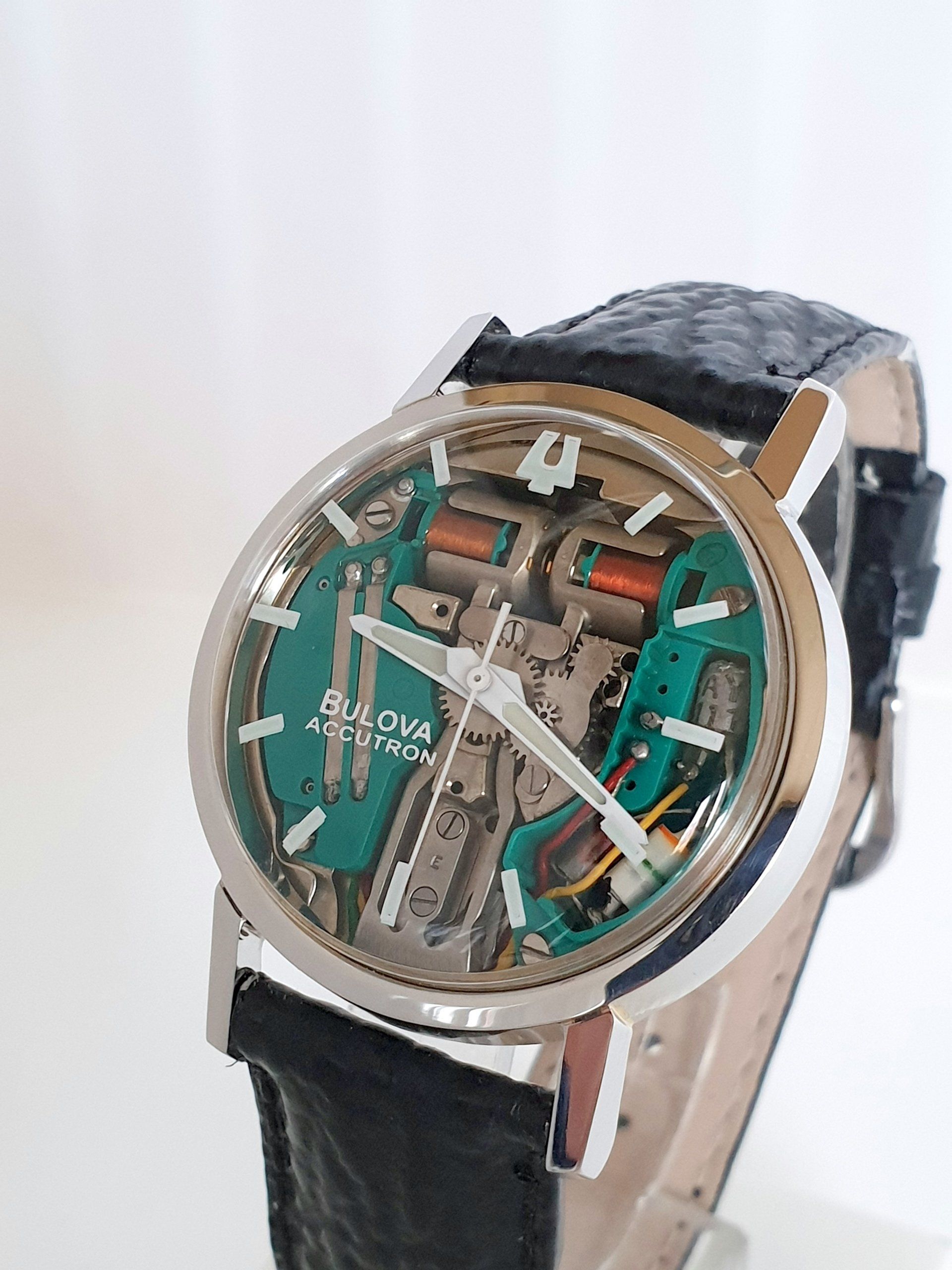 Skeleton-style wristwatch with teal and silver details on a black leather strap