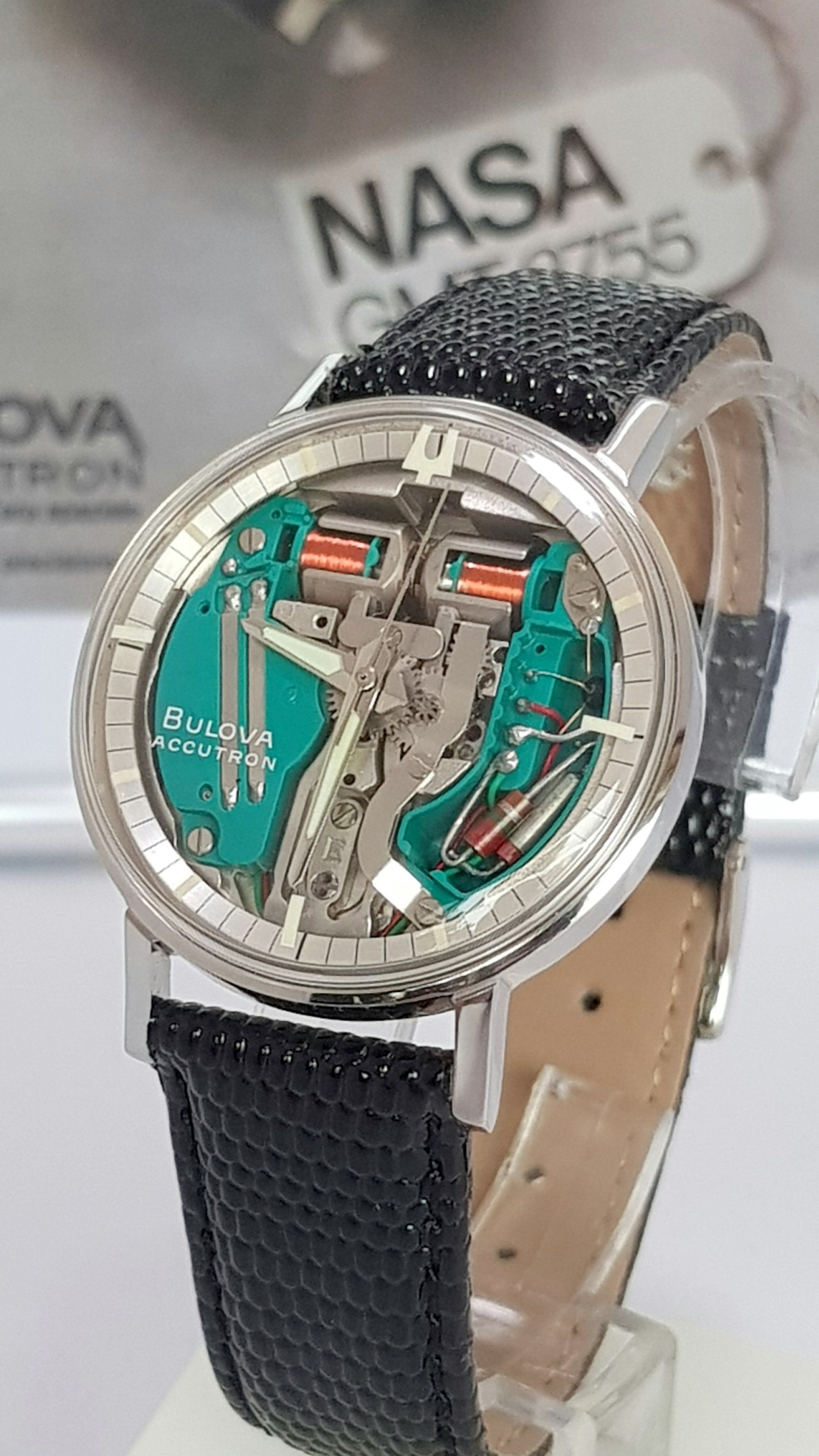 Silver NASA-themed wristwatch with green dial on a black strap