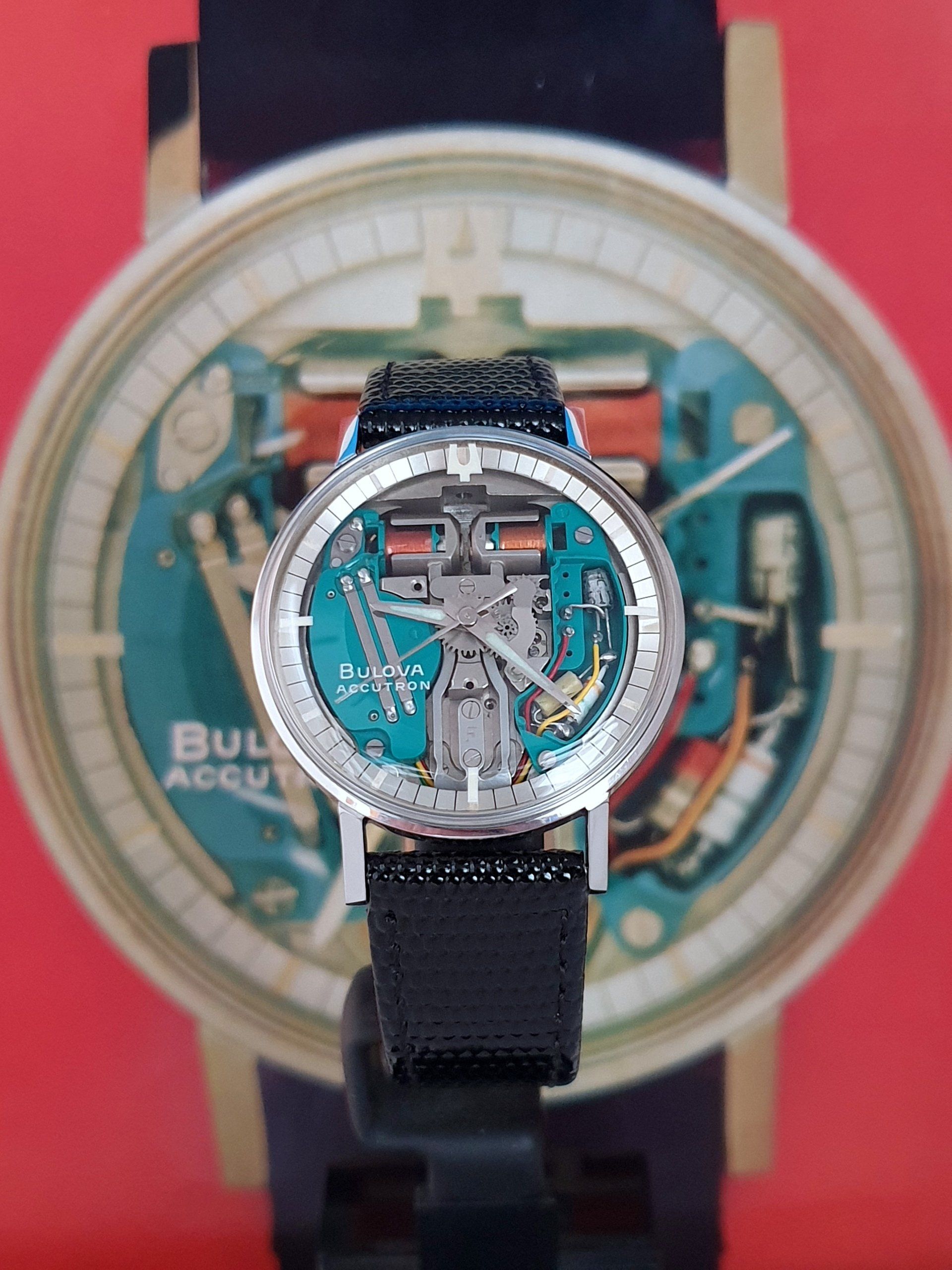 Blue Bulova watch with black strap in front of a larger matching watch display