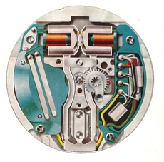 Cross-section of a small mechanical watch movement with visible gears and springs in silver, teal, and copper.