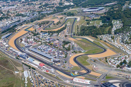 Luchtfoto van het Circuit de la Sarthe in Le Mans, Frankrijk. Het circuit slingert zich door het landschap, omringd door gebouwen en bomen.