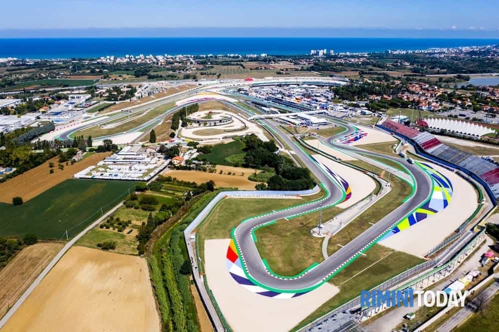 Luchtfoto van het Misano World Circuit Marco Simoncelli, een racecircuit in Italië. De baan, de tribunes en het omliggende landschap zijn zichtbaar onder een heldere hemel.