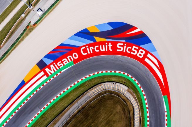 Bovenaanzicht van het Misano Circuit Sic58-racecircuit, met een beschilderde hoek met kleurrijke geometrische patronen en de naam van het circuit.