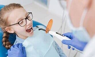 Lovely ginger girl sitting in chair for special procedure — Dental Service in North Tonawanda, NY Lovely ginger girl sitting in chair for special procedure — Dental Service in North Tonawanda, NY