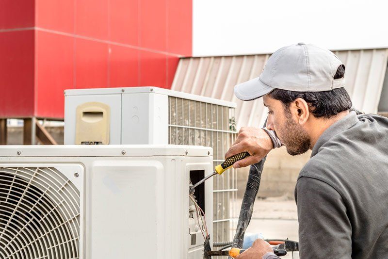 Man Fixing Air Condition — Hopewell, PA — Mark A. Redinger Plumbing and Heating Inc. Man Fixing Air Condition — Hopewell, PA — Mark A. Redinger Plumbing and Heating Inc.