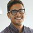 a man wearing glasses is smiling for the camera .
