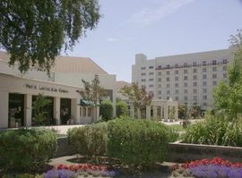 Exterior view of a performing arts center and hotel on a sunny day with greenery.