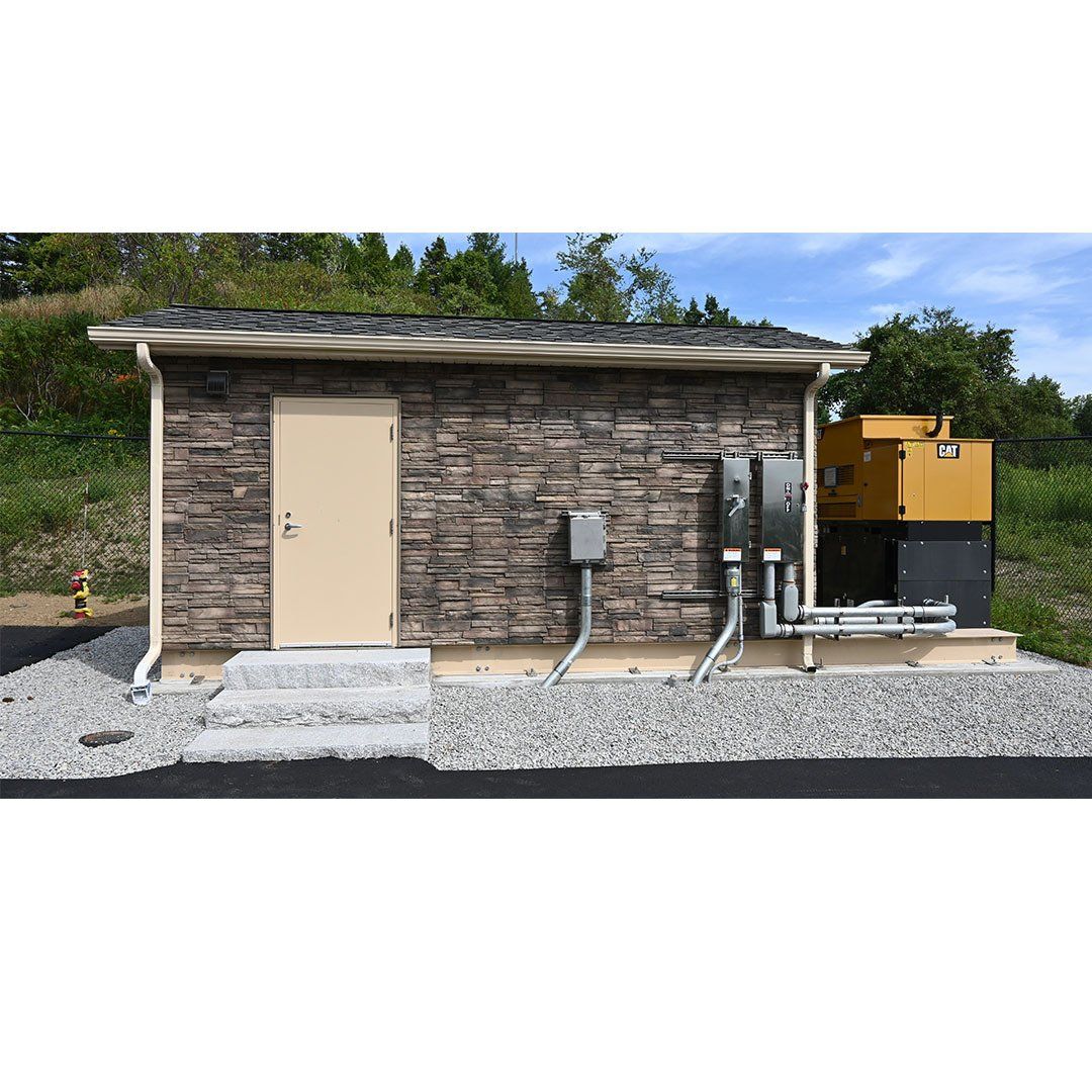 A small brick building with a door and a lot of wires coming out of it.