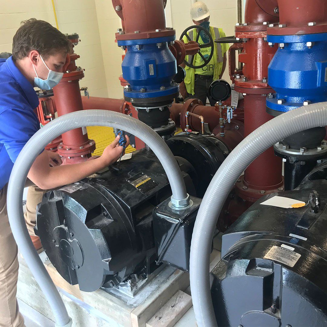 A man wearing a mask is working on a pump in a factory.