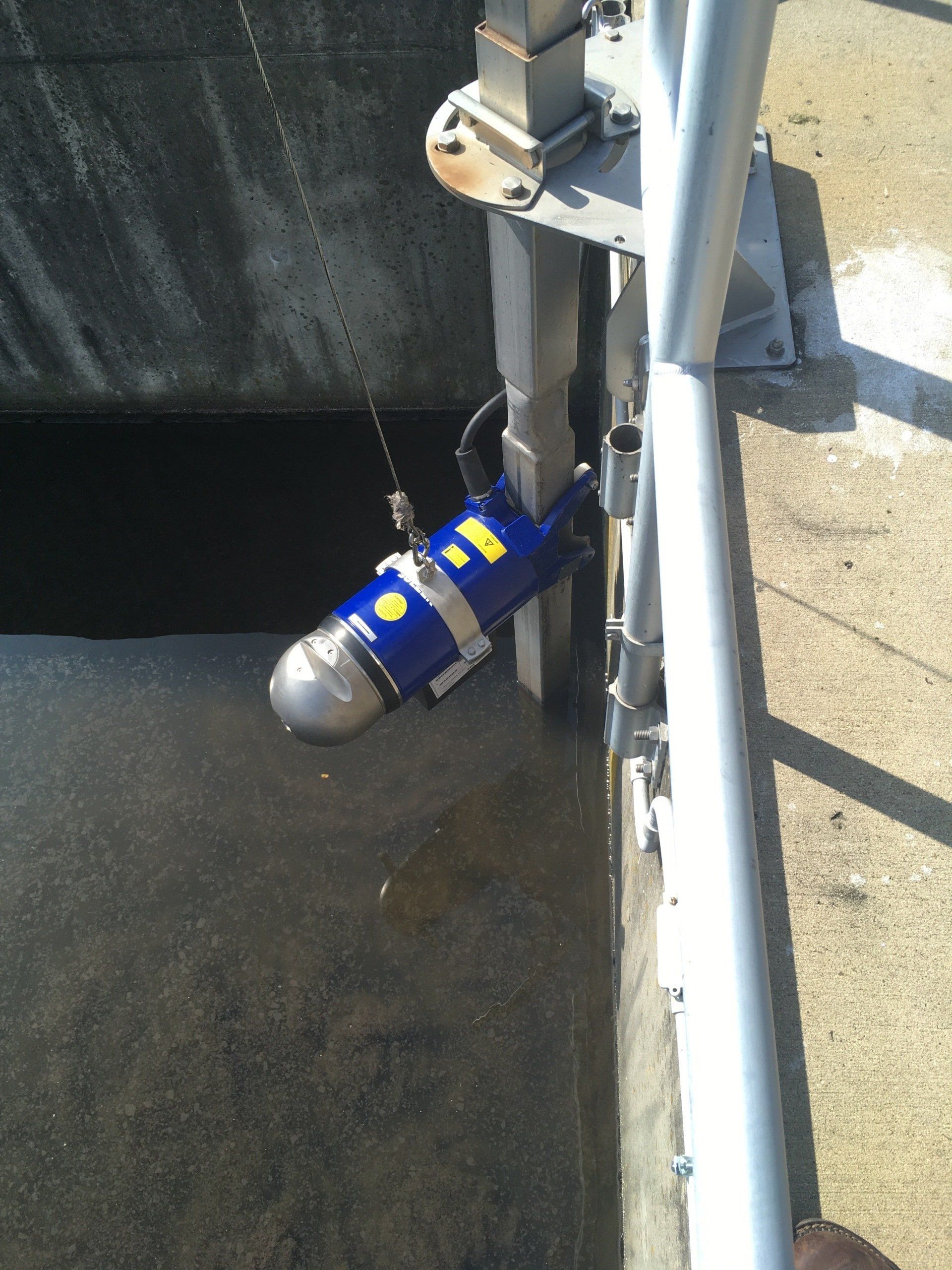 A blue object with yellow letters is attached to a metal pole