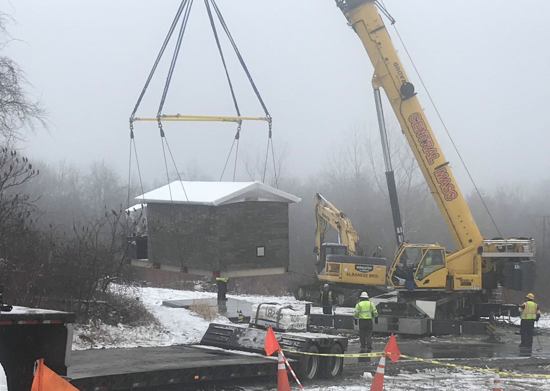 A yellow crane is lifting a building in the snow
