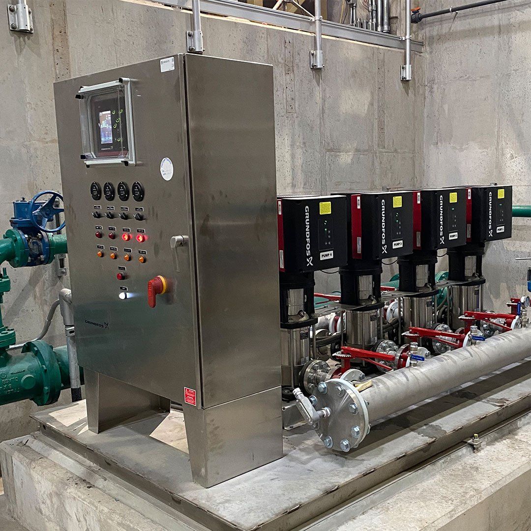 A stainless steel control panel is sitting next to a row of pumps.