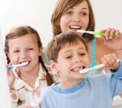 Mother and two children brushing teeth — Family Dentistry in Cheyenne, WY Mother and two children brushing teeth — Family Dentistry in Cheyenne, WY