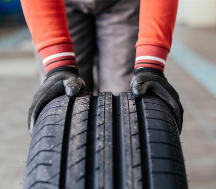 Auto Body Shop — Hand Pushing a Black Tire in Mount Vernon, NY