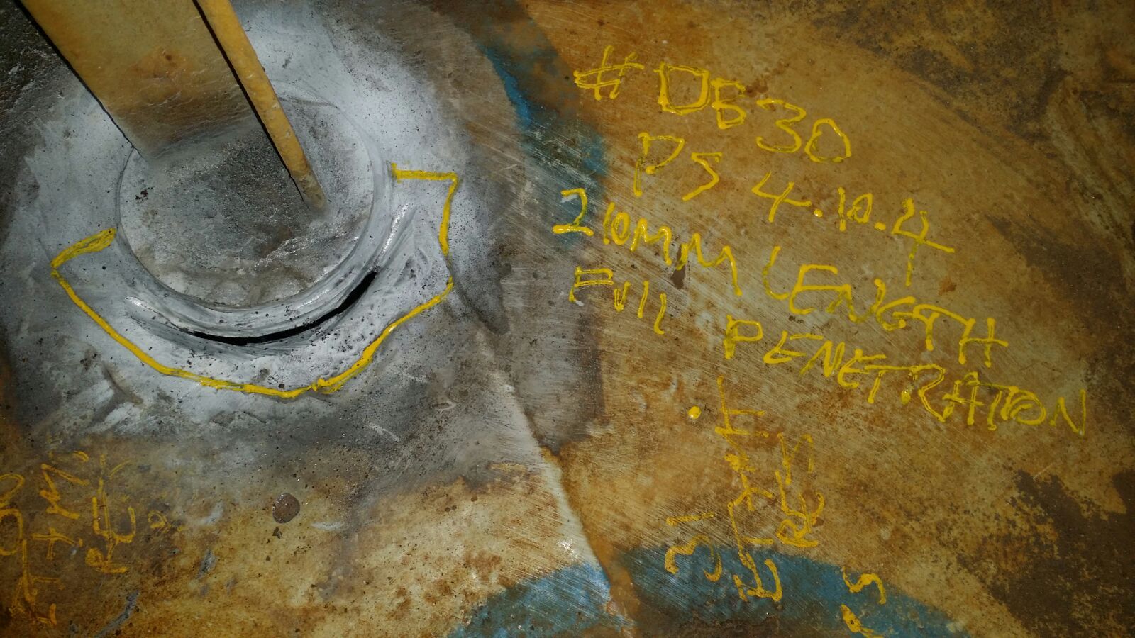 Close-up van industriële apparatuur, met gele markeringen en handgeschreven tekst op een verweerd oppervlak.