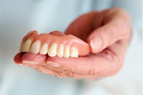 Dentures and Partials hand holding dentures