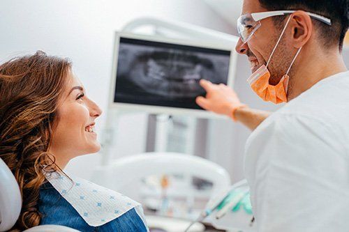 Preventive Care Male dentist pointing at X-rays to female patient