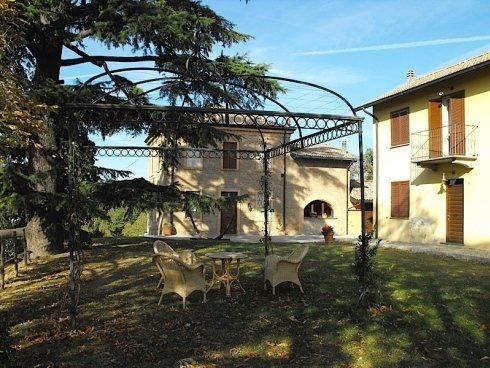 Il giardino con la pergola, i mobili e al fondo la tenuta