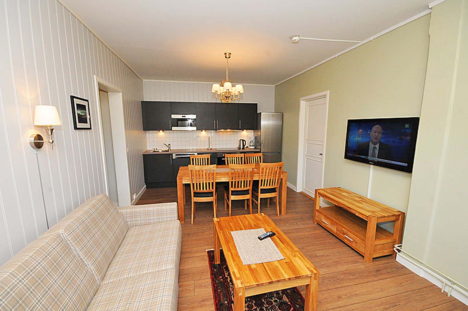 En stue med sofa , bord , stoler og flatskjerm - tv.