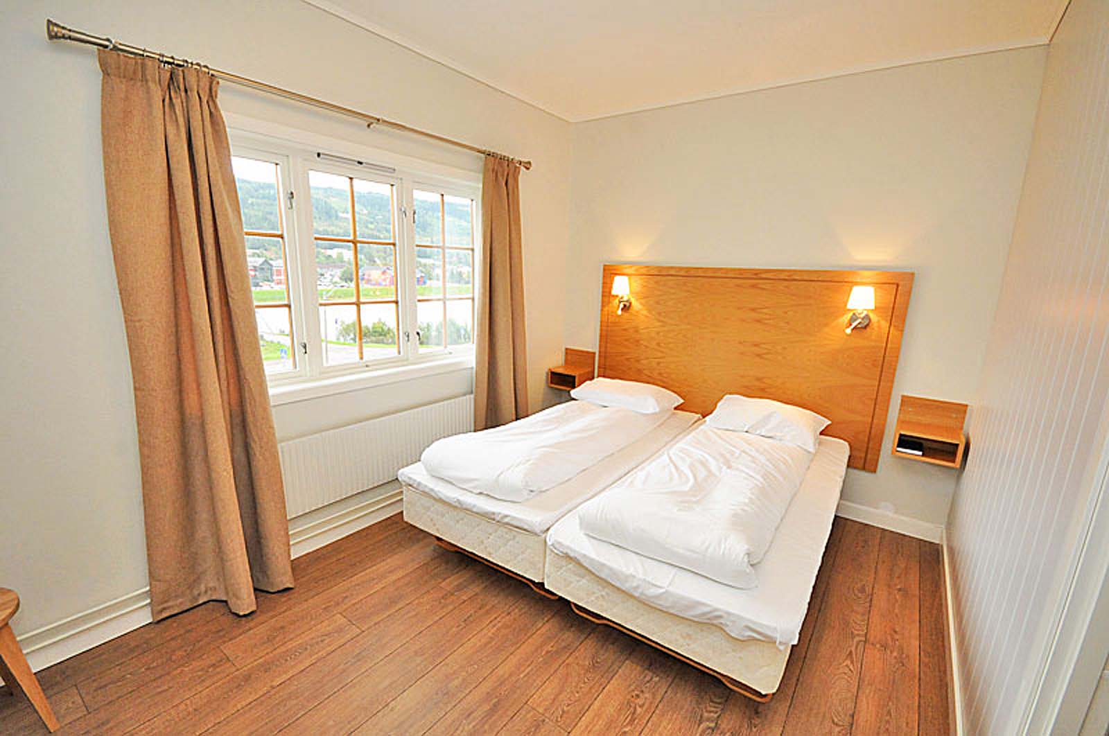 Et hotellrom med to senger og et vindu.