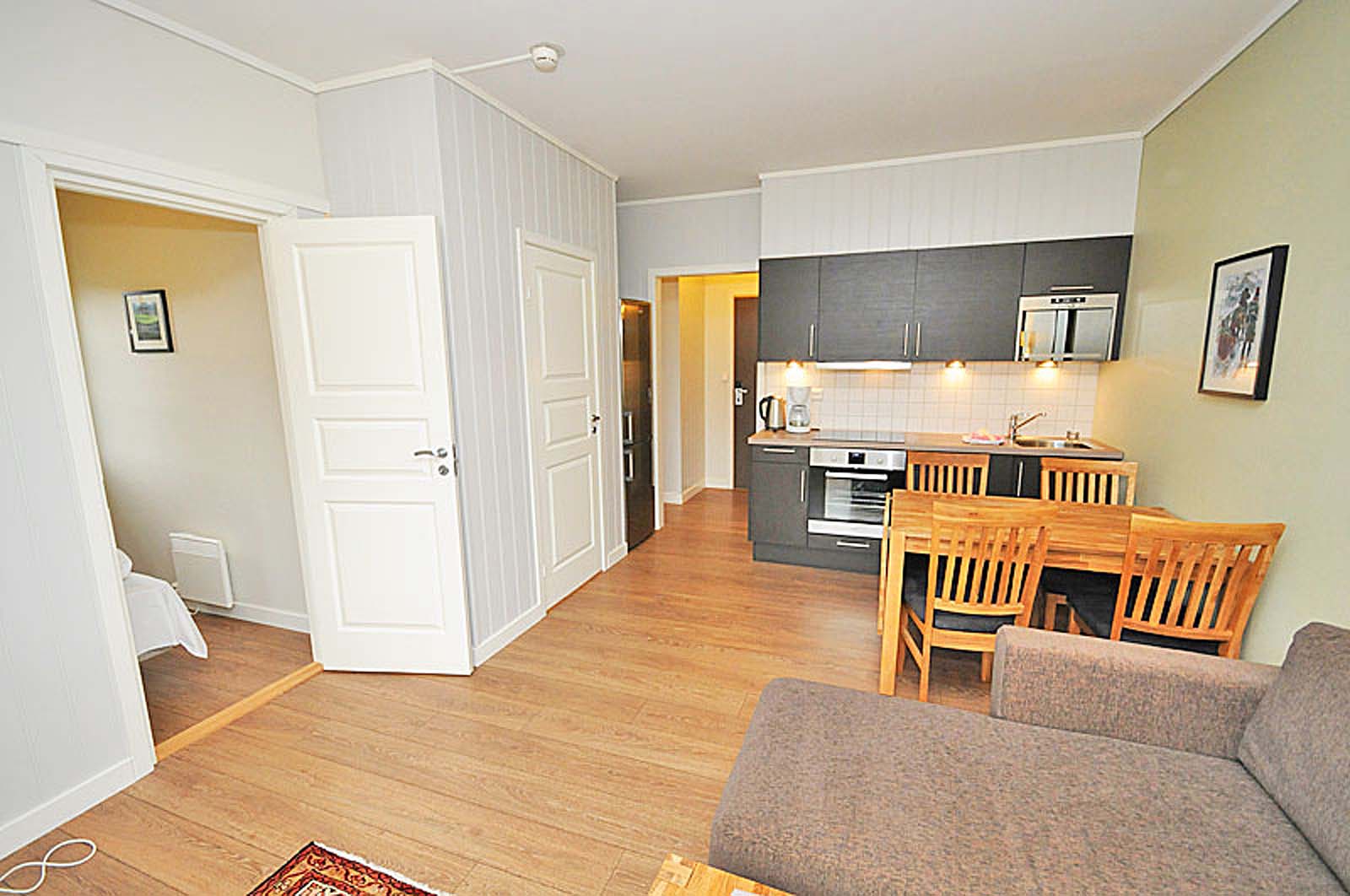 En stue med en sofa, et bord og stoler og et kjøkken