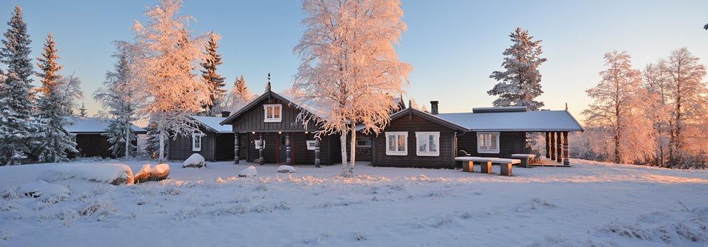 En gruppe hus som sitter på toppen av et snødekt felt.