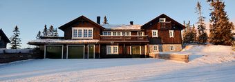 Et stort hus sitter på toppen av en snødekket bakke.
