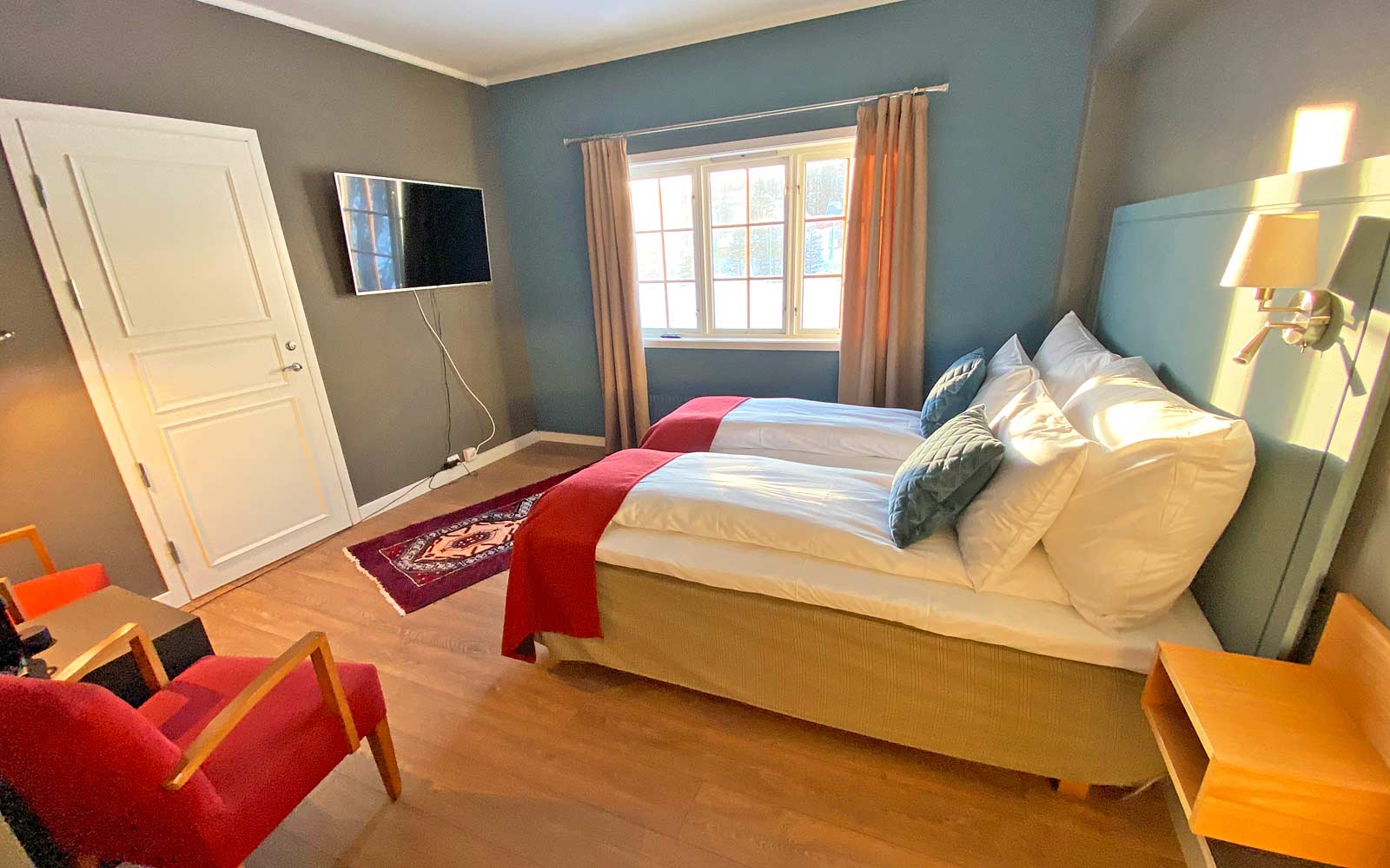 Et hotellrom med to senger, en stol og en TV.