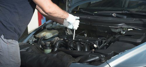 Meccanico auto mentre lavora su un motore di una macchina