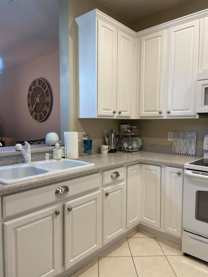 White kitchen cabinets and appliances with light countertops and a sink.