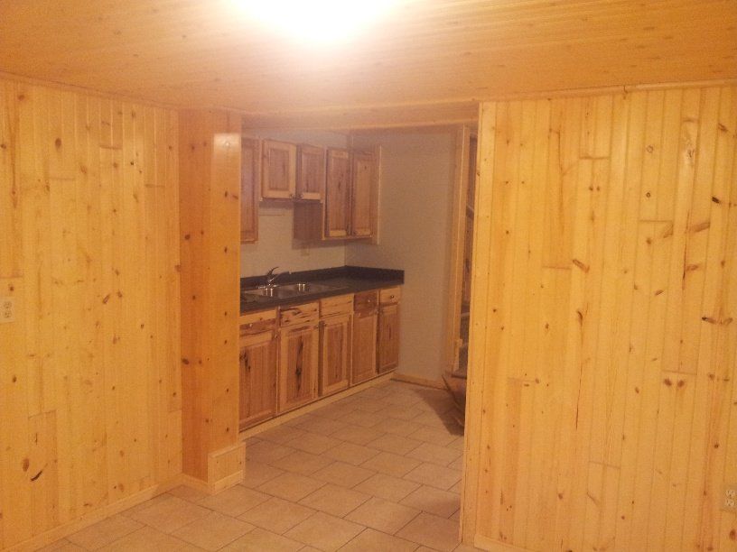 Interior view of a kitchen with light wood paneling, cabinets, and tile flooring.