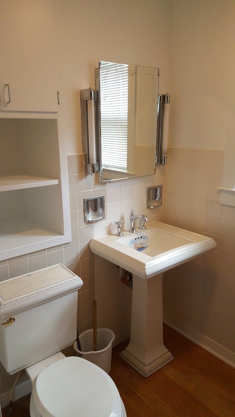 Bathroom with white pedestal sink, toilet, medicine cabinet, and built-in shelving.