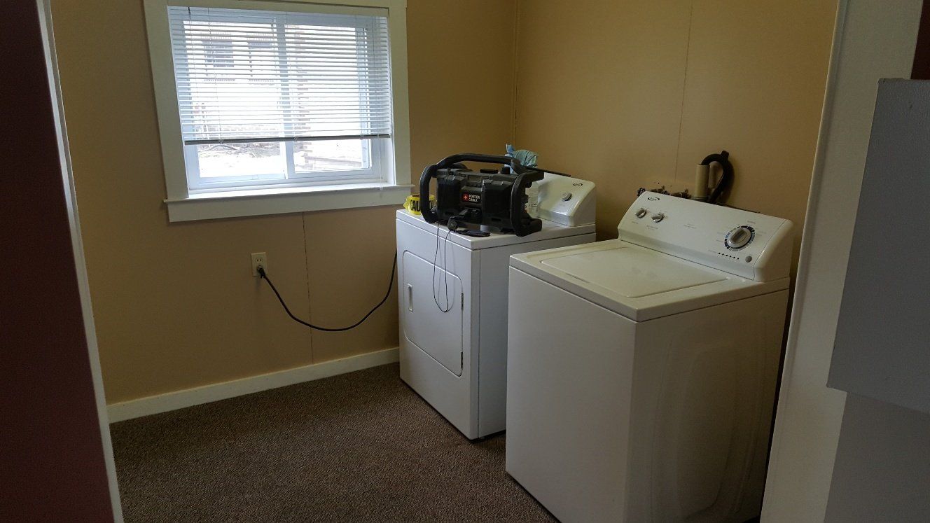 Laundry room with a washing machine, dryer, and window.