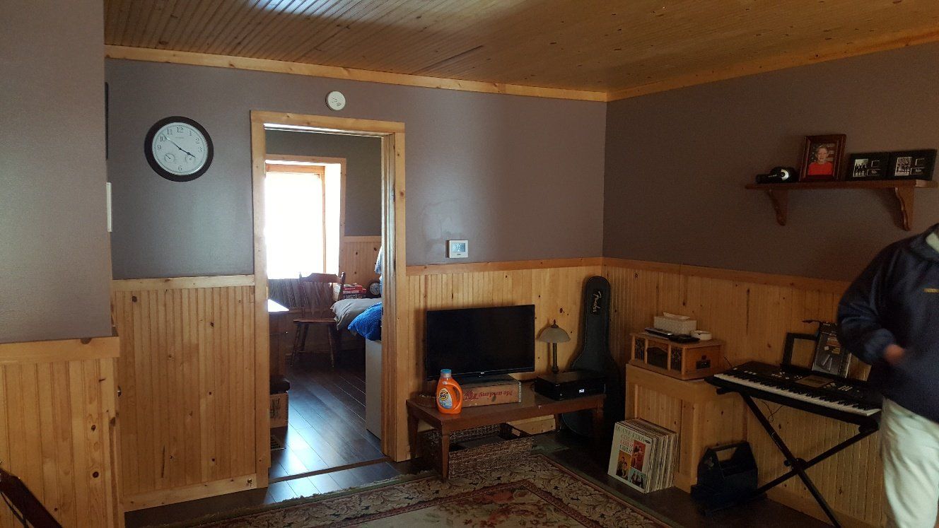 Interior view of a room with brown walls and wood paneling. A person stands near a keyboard.