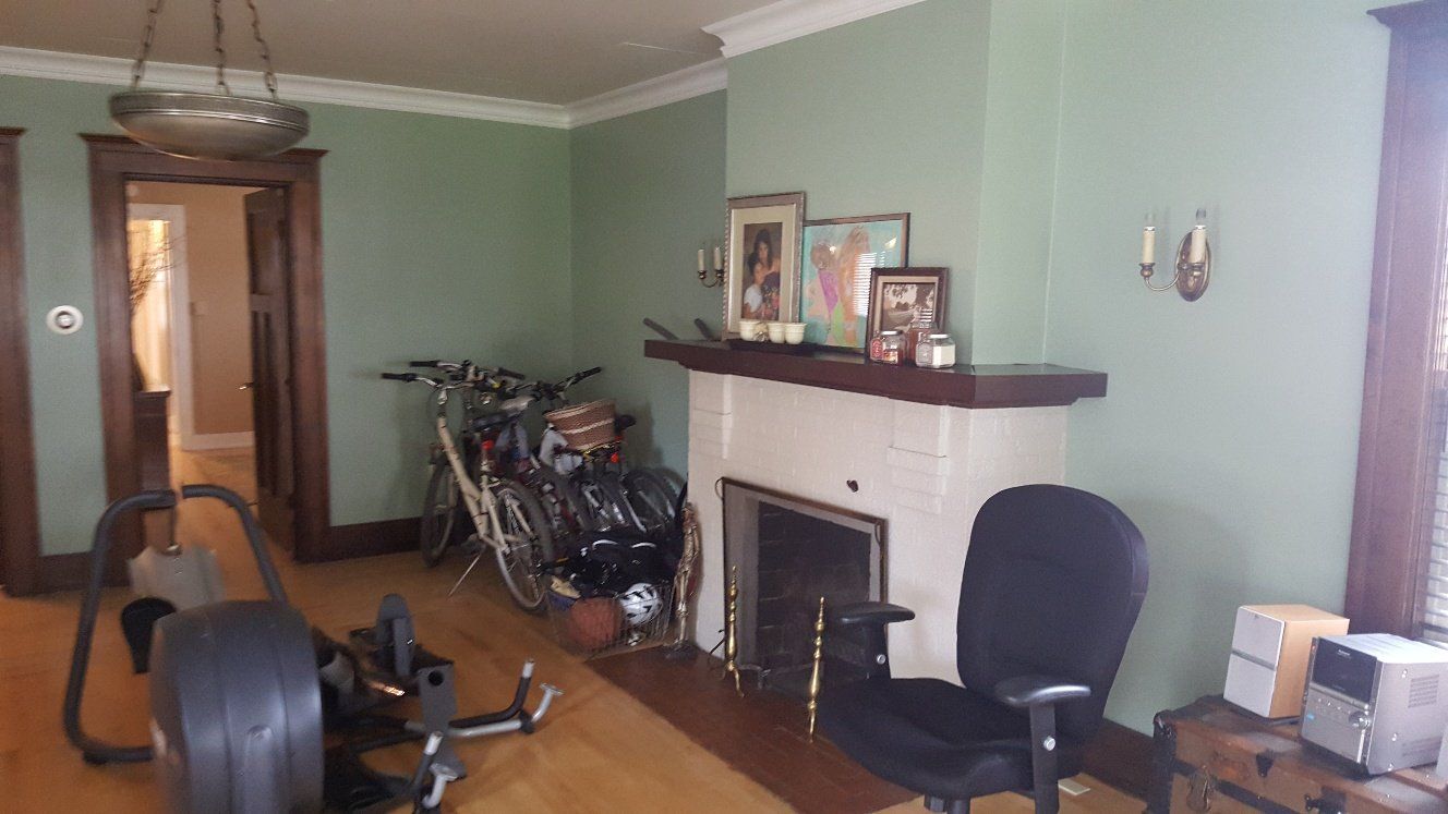 Room with fireplace, exercise equipment, and bicycles; green walls and wood trim.