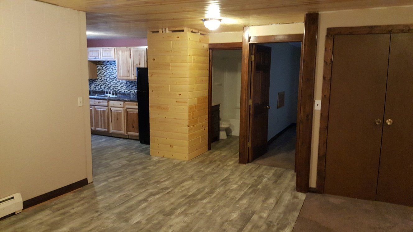 Interior view of an apartment with wood floors, cabinets, and a tall wooden column.