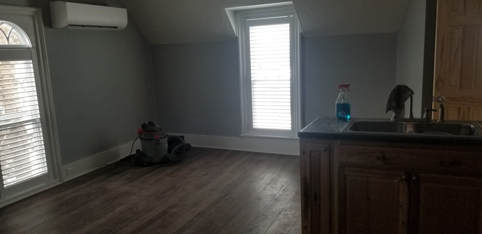 A sparsely furnished room with a sink and cabinets, window and an air conditioner unit.
