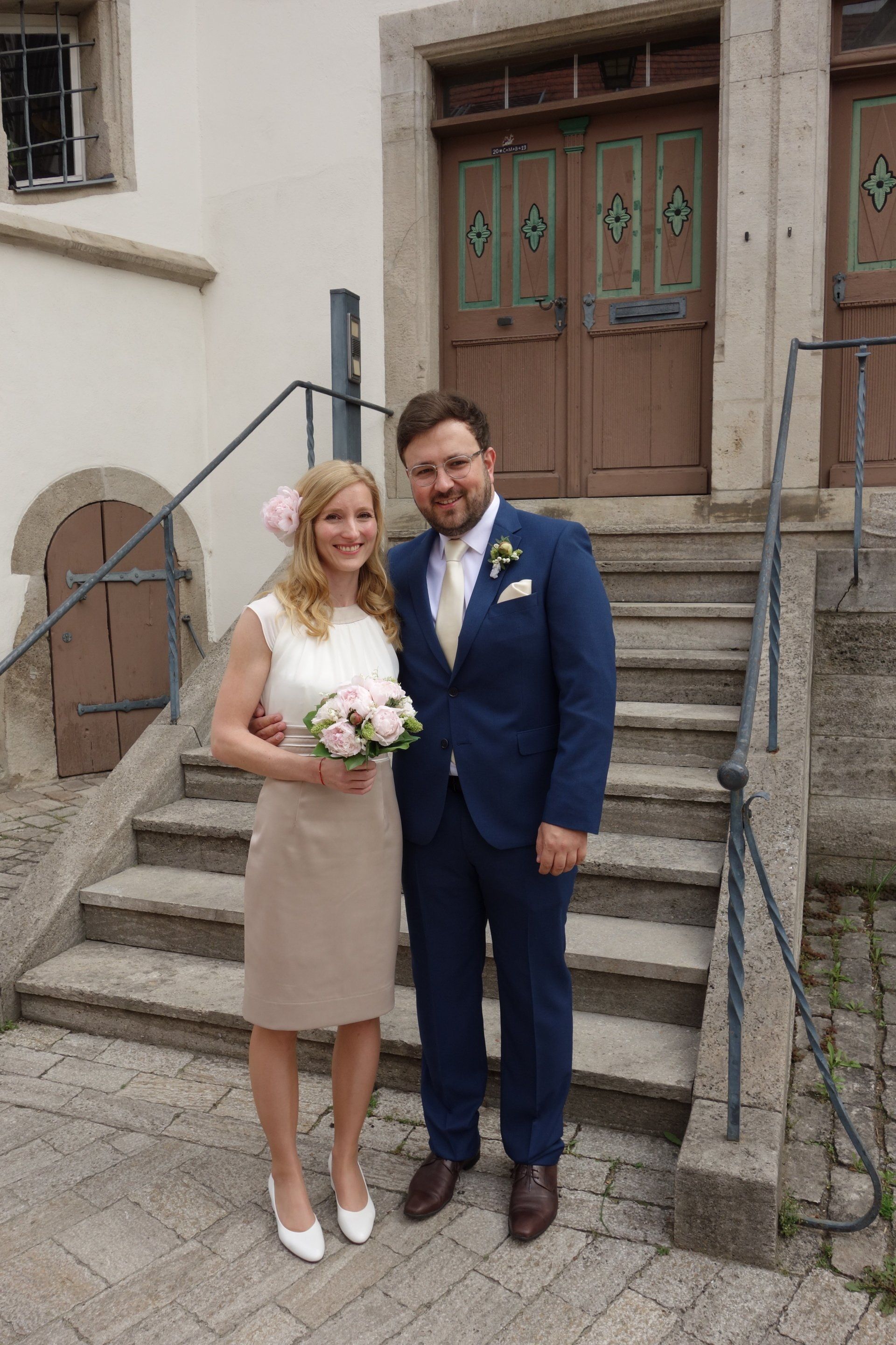 Eine Braut und ein Bräutigam posieren vor einem Gebäude für ein Foto.